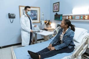 A doctor discussing with a patient in a hospital bed