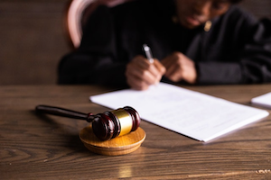 Person signing a paper with a gavel at the side